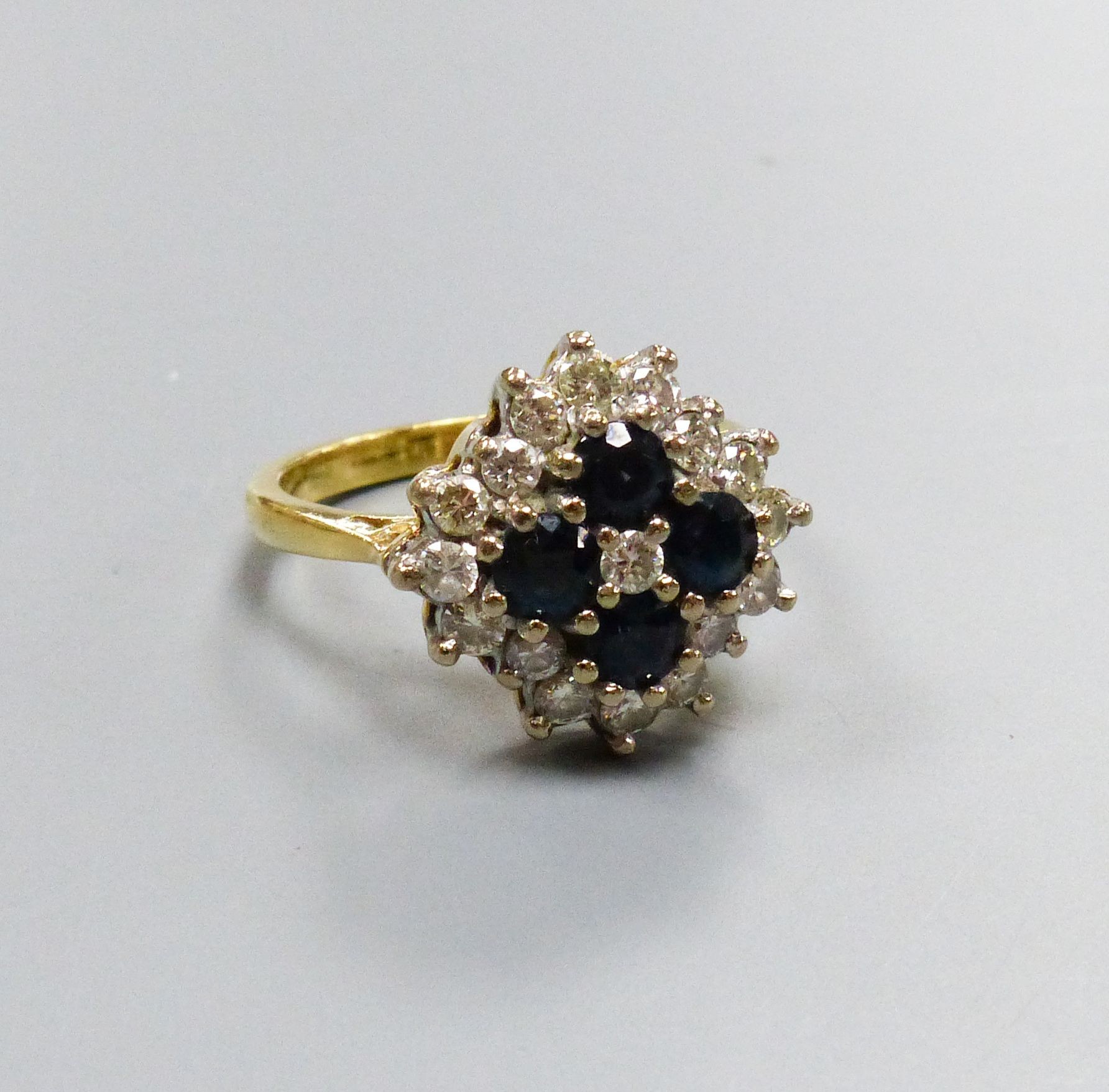 A modern 18ct gold, sapphire and diamond set diamond shaped cluster ring, size M/N, gross 6.1 grams.